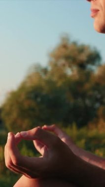 Gün batımında meditasyon yapan yoga adamı portresi. Dikey video. Erkek, yoga minderinde lotus pozu verip meditasyon yapıyor. Rahatlama ve rahatlama aktivitesi. Fitness etkinliği
