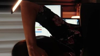 Çalışma masasında oturan ve bilgisayar ekranına bakan bir kadının arka plan görüntüsü. Dikey video. Ev ofisinde çalışan, bilgisayar kullanan, dijital bilgisayar ekranına bakan serbest çalışan bir kadın.