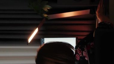 Kadın işten eve gelirken kablosuz kulaklık takıyor. Dikey video. Bilgisayar ekranının önünde oturan, kulaklık takan, bilgisayar üzerinde çalışmaya başlayan genç bir serbest çalışan.