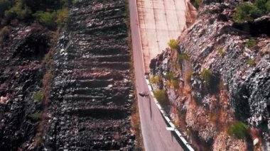 Bisikletçi bisikletiyle pikoresk dağ manzarasında geziyor. Dikey video. Bisiklete binen, pedalları yokuş yukarı iten biri. Bisikletçi sporcu dışarıda antrenman yapıyor, yoğun kardiyo egzersizleri yapıyor.
