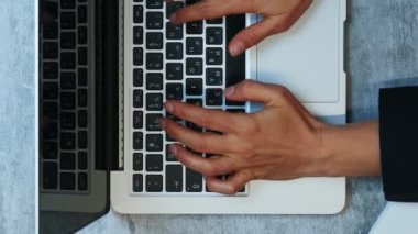 Eller iş gününden sonra dizüstü bilgisayarı kapatıyor. Dikey video. Ofis masasında dizüstü bilgisayar kullanan kadın. Dizüstü bilgisayarda yazı yazan kadın eller, üst görünüm. Uzak çalışma