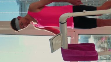 Komik kıyafetli genç adam koşu bandında yürümeye başlıyor. Dikey video. Evde koşu bandında pembe spor üst düzey antrenman yapan sporcu bir erkek. Fitness aktivitesi. Etkin spor konsepti