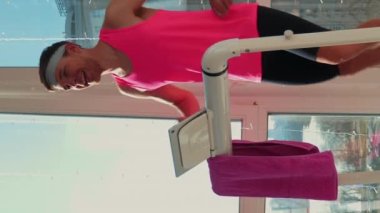 Koşu bandında koşan bir adam. Genç, zinde bir erkek koşu bandında koşuyor. Dikey video. Evde antrenman yapan, spor yapan biri. Aktif sağlıklı yaşam tarzı. Spor konsepti