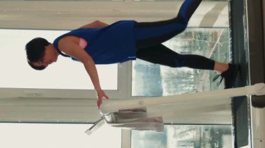 Koşu bandında koşan kadın. Dikey video. Evde koşu bandında koşan atletik sporcu bir kadın, fitness kardiyo egzersizleri yapıyor. Ev ödevi aktivitesi. Aktif sağlıklı yaşam tarzı