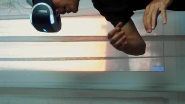 Sanal oyun oynarken havaya dokunan VR kulaklıklı bir adamın portresi. Dikey video. Genç heyecanlı adam video oyunu oynuyor, sanal gerçeklik gözlükleriyle sanal dünyayı keşfediyor.