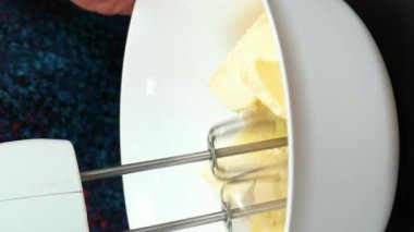 Elektrikli mikser kullanarak tereyağlı krema yapıyorum. Pasta için krema pişiren kadın fırıncı. Dikey video. Şekerci pastaya tereyağı kreması hazırlıyor. Evde yemek pişirmek. Tereyağıyla şekeri karıştırıyorum.