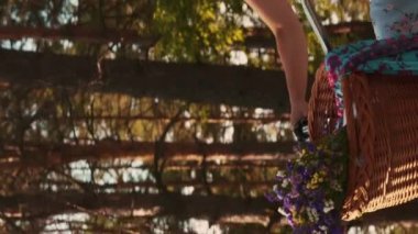 Hasır şapkalı ve retro bisiklete binen alımlı genç bir bayan. Dikey video. Yeşil Park 'ta klasik bisiklete binen neşeli gülümseyen kadın yaz tatilinin tadını çıkarıyor. Boş zaman aktivitesi