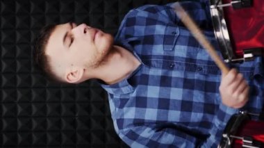Davulcu müzik stüdyosunda davul çalıyor. Dikey video. Davul çalan, şarkı besteleyen genç bir müzisyen. Perküsyon enstrümanları çalıyorum. Müzik konsepti