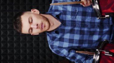 Prova stüdyosunda davul ve zil çalan müzisyen. Dikey video. Erkek davulcu müzik stüdyosunda davul çalıyor. Perküsyon enstrümanları çalan adam. Müzik konsepti