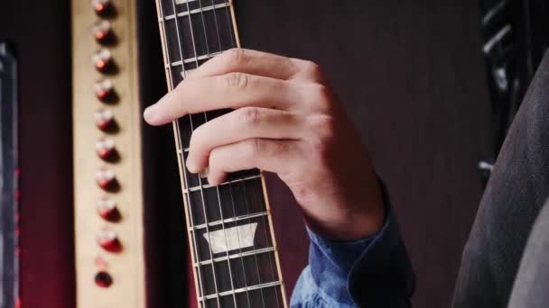 ギタリストがギターの弦の上で演奏している 垂直ビデオ リハーサルスタジオでエレキギターで曲を演奏するミュージシャン ステージでギターの新しいコードを練習する男 — ストック動画