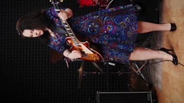 Stüdyoda şarkı söyleyen ve elektro gitarda çalan kadın şarkıcı. Gülümseyen büyüleyici kadın ses kayıt stüdyosunda şarkı söylüyor ve kayıt yapıyor. Müzik konsepti