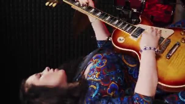 プロのスタジオでエレキギターを弾く女性ミュージシャン 垂直ビデオ 女性が音楽リハーサルスタジオでギターで歌を歌う精力的な女性の歌と楽器を演奏 — ストック動画
