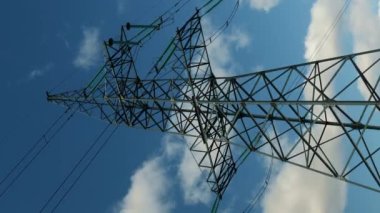Elektrik hatları ve pilonlar açık mavi gökyüzüne karşı. Dikey video. Voltaj dağıtım kabloları olan uzun pilonlu bir elektrik santrali. Dönüştürme istasyonu ve elektrik kulesi