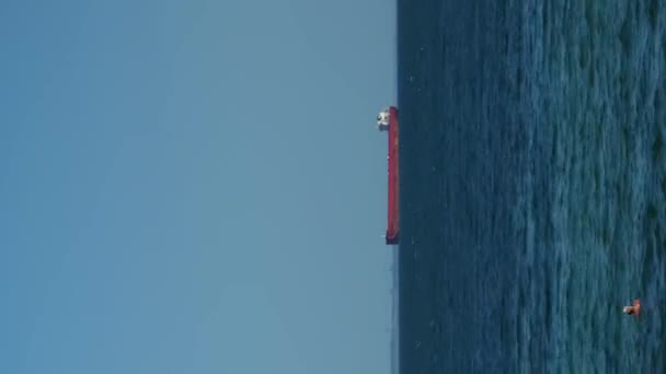在海上漂流的红色货船的时差 垂直录像 货物运输 在蓝天的映衬下航行的货船在海上航行 国际后勤运输 — 图库视频影像