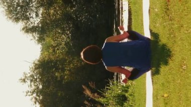 Yoga meditasyonu yapan bir kadın gün doğumunda yoga minderinde oturuyor. Dikey video. Genç dişi sporcu göl ya da nehir kenarında meditasyon yapıyor, derin derin nefes alıyor ve temiz havanın tadını çıkarıyor. Gün batımında yoga.