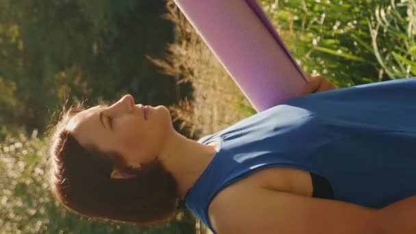 요가를 배우고 공원을 미소짓는 영상입니다 선수인 암컷은 공원에서 운동을 매트를 — 비디오