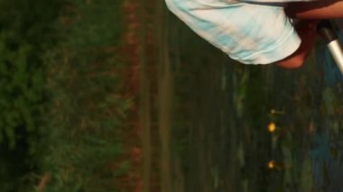 Yazın gölde kayak yapan bir kadın. Dikey video. Boş zaman aktivitesi. Aktif spor. Genç atletik kadın nehirde kano üzerinde yüzüyor, aktif hafta sonunun tadını çıkarıyor. Açık hava aktivitesi.