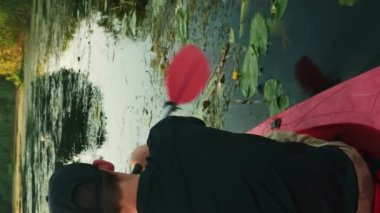 Aktif erkek kano günbatımında. Genç sporcu yaz güneşli bir günde kano üzerinde kürek çekiyor. Dikey video. Spor aktivitesi. Boş zaman aktivitesi. Açık hava eğlencesi. Aktif sağlıklı yaşam tarzı