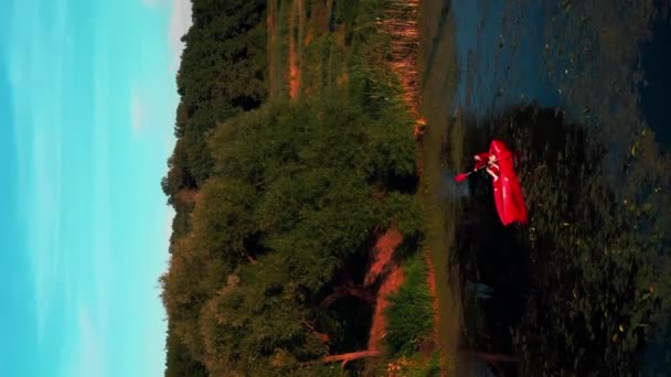 日没のアクティブな女性カヤック スポーツ活動 垂直ビデオ 川でカヤックを漕ぐ女性観光客は 自然と美しい夏の夕日を楽しんでいます 観光のコンセプト — ストック動画