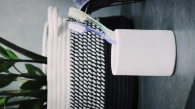 Banyodaki beyaz bardaktan diş fırçası alan kadın. Dikey video. Kadın ellerine yakın, plastik diş fırçası alın, fırça dişleri için hazırlanın. Her gün sağlıklı rutin