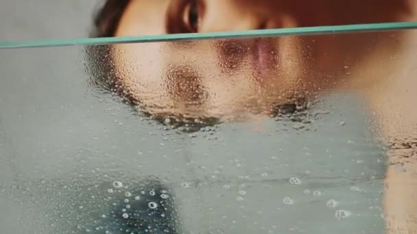 女性用洗涤剂 喷雾和抹布清洗淋浴玻璃 垂直录像 妇女清洗淋浴间 — 图库视频影像