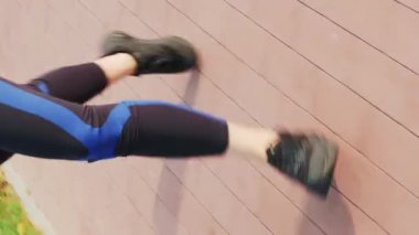 Tozluklu kadın bacakları ve parkta koşan spor ayakkabıları. Dikey video. Sportif atletik kadın dışarıda koşuyor, kilo vermeye çalışıyor. Fitness aktivitesi. Kardiyo egzersizleri.