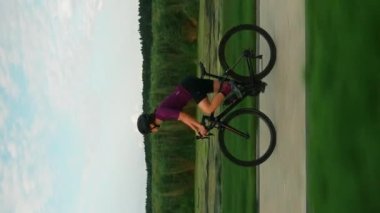 Profesyonel bisikletçi bisikletle pedal çeviriyor. Dikey konsept. Gün batımında bisiklet süren bir kadın. Spor motivasyonu. Aktif sağlıklı yaşam tarzı. Spor antrenmanı.