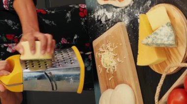 Pizza için peynirleri rendeleyin. Dikey video. Evde nefis İtalyan pizzası hazırlayan bir kadın, ızgara peynir. Sağlıklı yemek yapma süreci. Aşçılık ve aşçılık konsepti