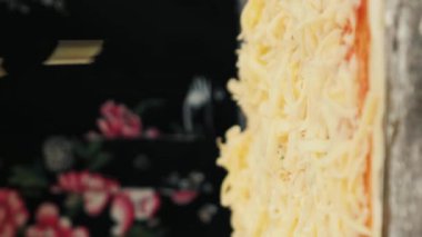Pizza hamuruna rendelenmiş peynir eklemek, ellerinizi ve peynirinizi kapatın. Dikey video. Kadın aşçı hamur üzerine peynir sürüyor, İtalyan pizzası yapıyor. Mutfak çevrimiçi dersleri. Yemek pişirme konsepti
