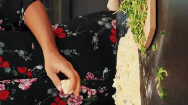 Ev yapımı pizza yapıyorum. Dikey video. Pizza hamuruna peynir döken bir kadın. Modern mutfakta geleneksel İtalyan pizzası hazırlayan bir kadın. İnternette yemek pişirme kursları. Mutfak konsepti