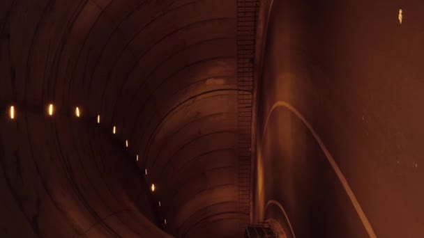 夜はトンネルを通る空の車道 バーティカルビデオ 暗いトンネル内の空のアスファルト道路 — ストック動画