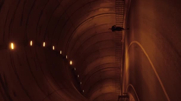 スポーツ活動 トンネルを通って速く走る男 バーティカルビデオ ダークトンネルで空のアスファルトカーロードで強力な男性アスリートのジョギングにフィットし 激しい心臓演習を行います ワークアウトトトレーニング — ストック動画