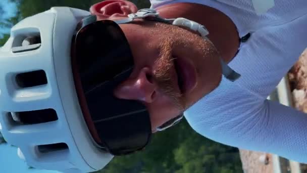 骑自行车的职业公路骑手的画像 垂直录像 身穿白色头盔和时髦自行车衣服的男性运动员骑自行车在山上 运动动机 密集的有氧运动训练 — 图库视频影像