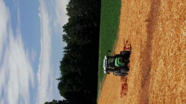 Sarı buğday tarlasında çalışan traktör biçicisini birleştirin. Dikey video. Tarım ve tarım sektörü kavramı. Ağır makinelerle çalışan yaz tarım alanı