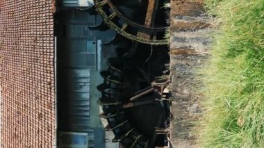 Eski değirmenin dönen ahşap tekerlekleri. Dikey video. İki büyük su değirmeni. Çalışan eski su değirmeni