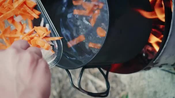 Kigyulladt Ételt Készít Természetben Kézzel Hozzá Répát Hagymát Vizes Edénybe — Stock videók
