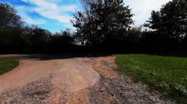 Tarlada çakıllı yolda bisiklet süren bisikletçilerin kişisel perspektifi. Bakış açısı. Çakıl yolu üzerinde bisiklet. Çakıl maceraları. Bisikletle seyahat. Dikey video