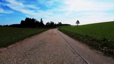 Bisikletçi yeşil alanda bisiklet sürüyor. Motosiklet süren motosikletli bir kadın. Bisiklet konsepti. Mavi gökyüzü ve tepelere karşı bisiklete binen adam. Bisiklet yokuşu. Aktif yaşam tarzı. Dikey video