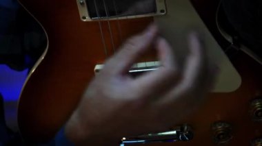 Elektro gitar çalan erkek elleri. İnsan eli ve parmakları başlıklı gitar panosunda. Karanlık odada elektro gitarla pratik yapan bir müzisyen. Müzik aleti konsepti. Dikey video.