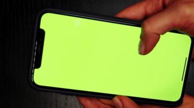 Masada yeşil ekranlı telefon. Kadın parmakları yeşil ekranlı cep telefonuyla mesaj yazıyor. Akıllı telefon kroma anahtar ekranı. İnternetteki kadın elleri haber kaydırıyor. Dikey video