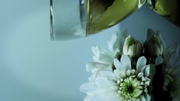 ガラスカップの有機クリームフラワーティー アロマティメ 健康的なハーブドリンク フラワーティーの回転カップ ガラスカップのカモミールティー リラックスする バーティカルビデオ — ストック動画
