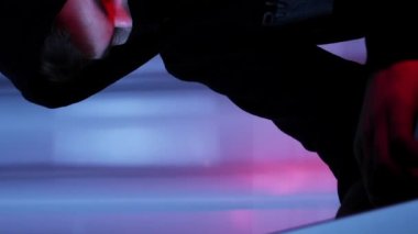 Siyah maskeli ve başlıklı bilgisayar korsanı karanlık odada oturmuş laptop ekranına bakıyor. Siyah kapüşonlu erkek kodlama ve programlama bilgisayarda. Hacker tuşları okşuyor. Güvenlik koruması. Dikey video