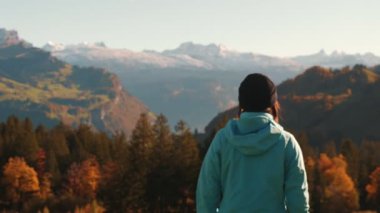 Dişi yürüyüşçü tepenin kenarında duruyor ve karlı İsviçre Alpleri dağlarına bakıyor. Spor elbiseli bir kadının İsviçre 'deki dağ ufkuna bakışının arka planı. Seyahat etmek ve dünyayı keşfetmek