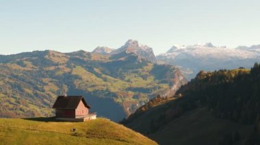 İsviçre Alpleri 'nin manzarası ve tepenin kenarında duran küçük bir ev. Sonbaharda karlı kayalık dağ zirveleri. Sonbaharda İsviçre dağları. Seyahat ve turizm kavramı