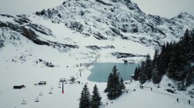 Trubsee Gölü 'ndeki Engelberg kayak merkezi, Titlis ve kayak pistleri. Karlı zirveleri ve sıradağları olan resimli bir kış manzarası. Aktif kış sporu. Açık hava aktivitesi. Seyahat kavramı