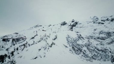 Engelberg 'deki Titlis Dağı taze karla kaplıydı. Teleferikli karlı kayalık dağların manzarası. Resmedilmeye değer bir kış manzarası. Dağ zirvesi ve ufuk çizgisi. Açık hava aktivitesi