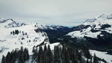 İsviçre 'deki Engelberg köyünün kışın hava manzarası. Taze karla kaplı dağ zirvelerindeki resmedilmiş kış manzarası. Dağ tepeleri ve sıradağlardan oluşan bir manzara. Kış sporu