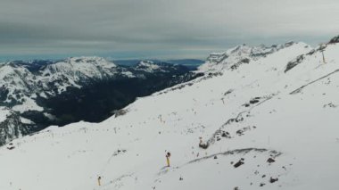 İsviçre 'deki popüler kayak merkezi, Engelberg, Titlis. İsviçre Alplerinde kar tepelerinde kayak yapan kayakçılar ve snowboardcular. Açılış kış kayak sezonu. Kayalık dağ zirveleri ve sıradağlardan oluşan bir manzara.