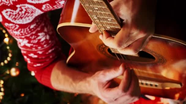 Man Feestelijke Rode Trui Spelen Kerstliedjes Gitaar Zitten Vloer Buurt — Stockvideo