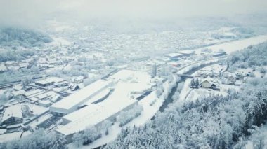 Kışın karla kaplı küçük bir köy. Karlı evler ve çam ağacı ormanı. Ağaçların, tepelerin ve evlerin olduğu resim gibi bir kış sahnesi. Doğa manzarası